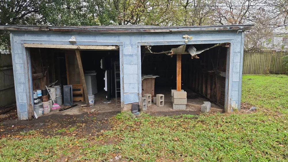 Exterior detached two-bay garage with open doorways during project
